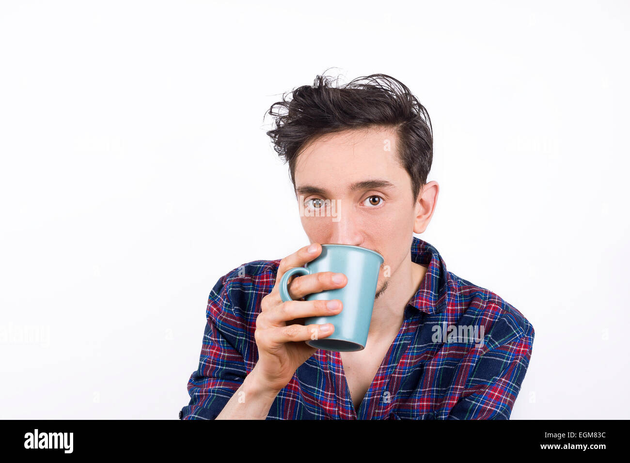 Isolated portrait of a man wearing pajamas and drinking his morning coffee, looking into the camera. Stock Photo