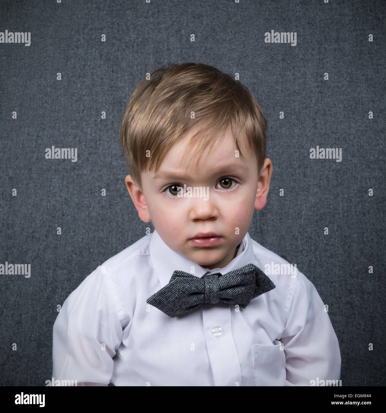 two year old boy looking straight into the camera wearing a grey bowtie Stock Photo