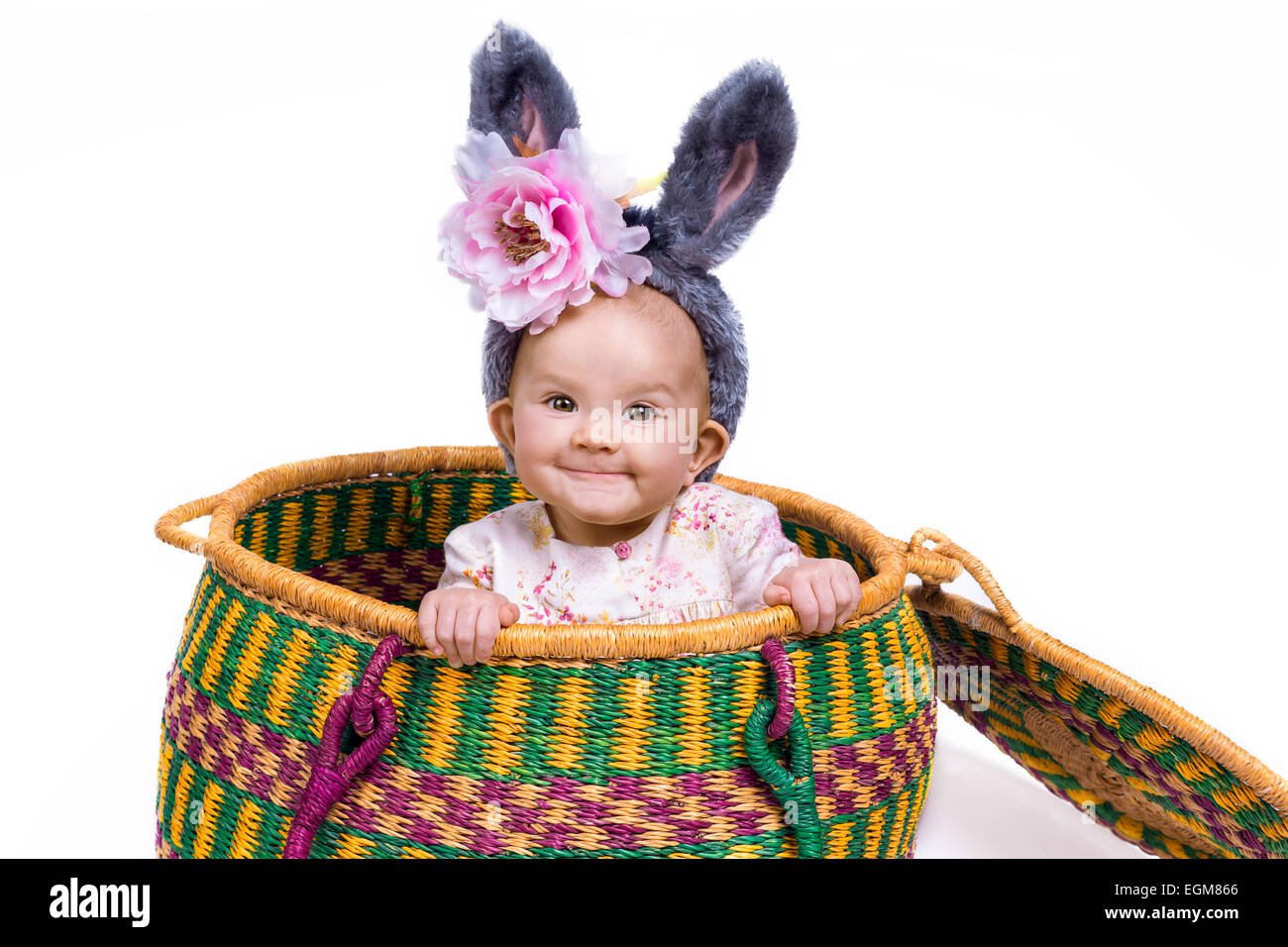 funny baby wearing bunny ears sitting in a basket Stock Photo
