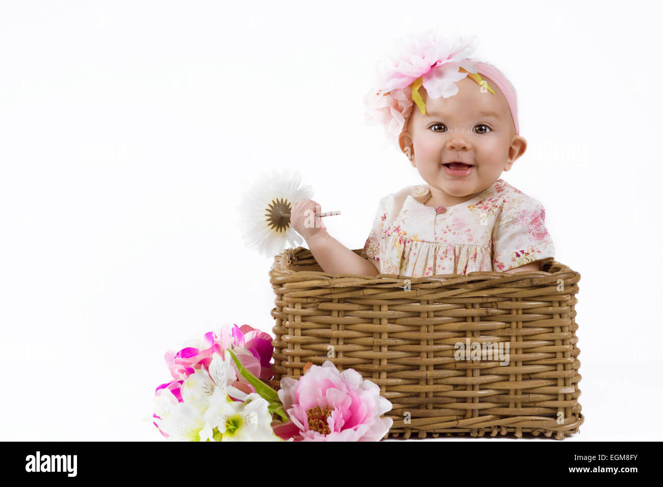 cute baby in a flower dress sitting in a flower basket Stock Photo