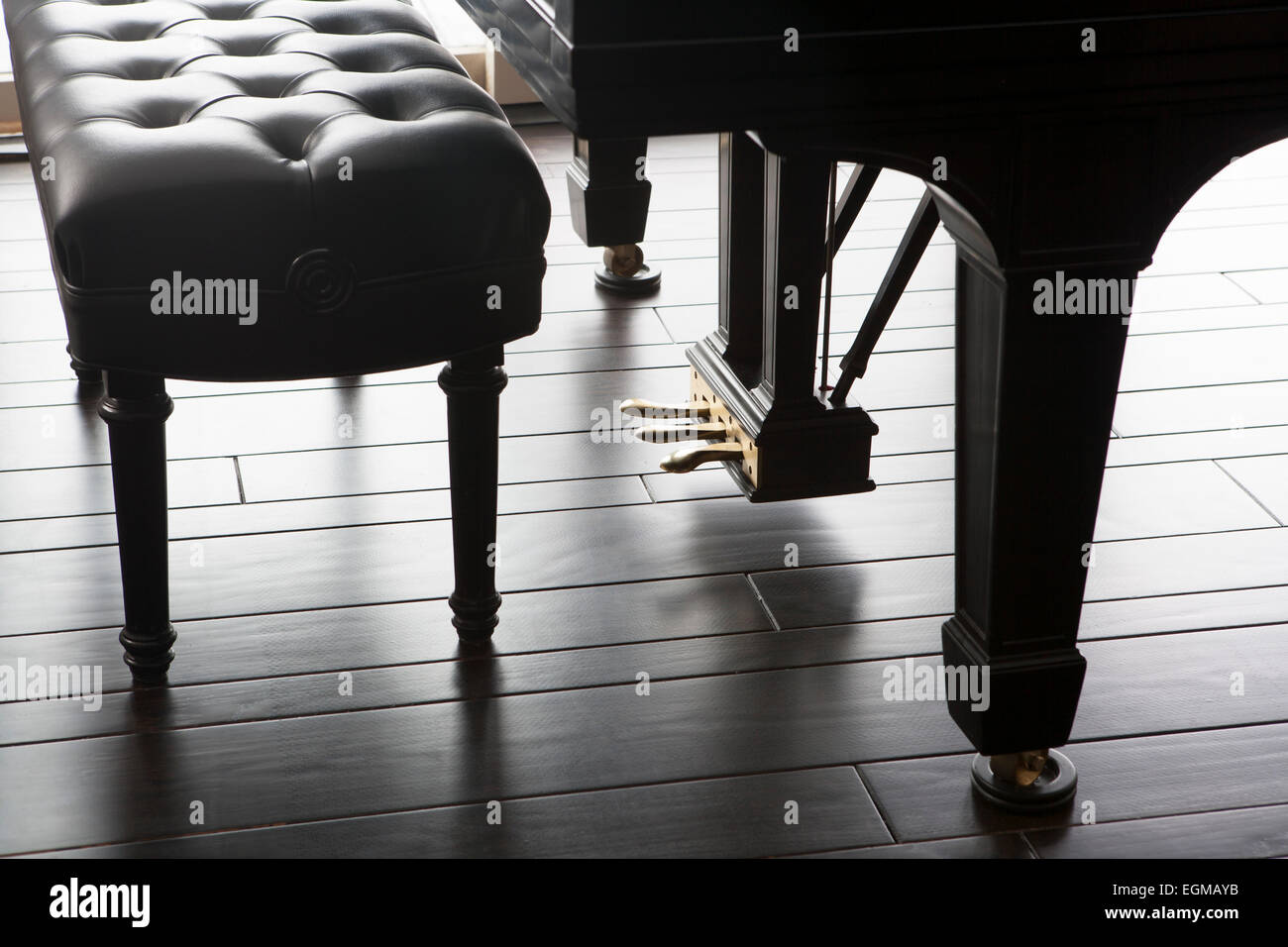 Grand Piano Foot Pedals and Bench on Dark Wood Floor Stock Photo