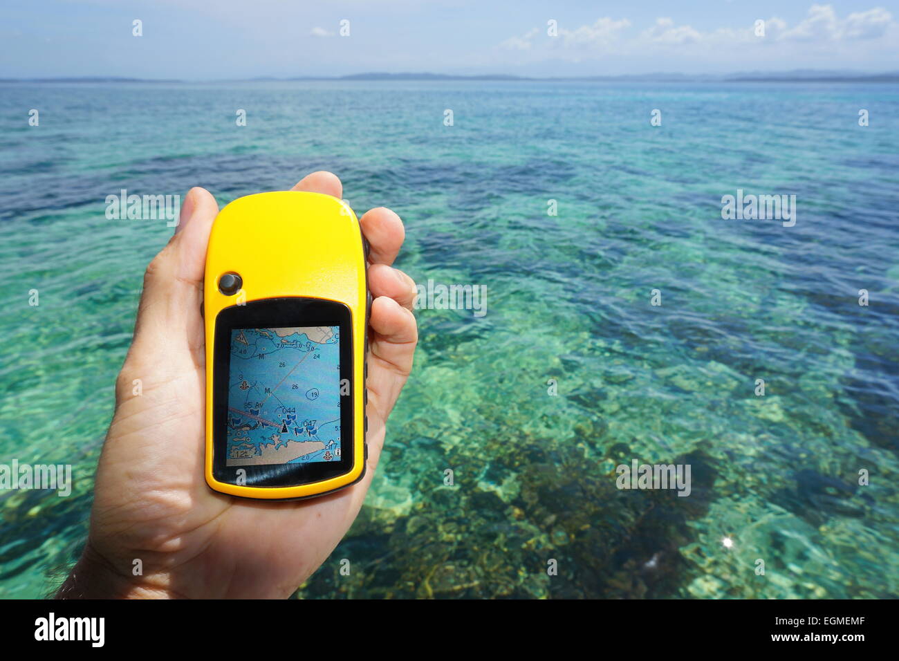 Hand holding a GPS navigator with marine map, over the water of the Caribbean sea Stock Photo