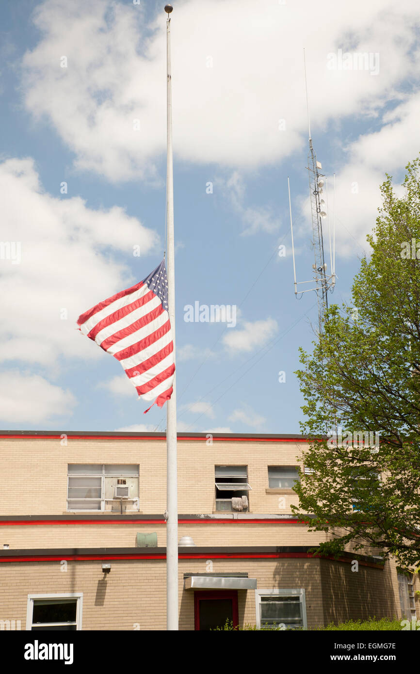 American flag flies at half staff next to a fire station in North