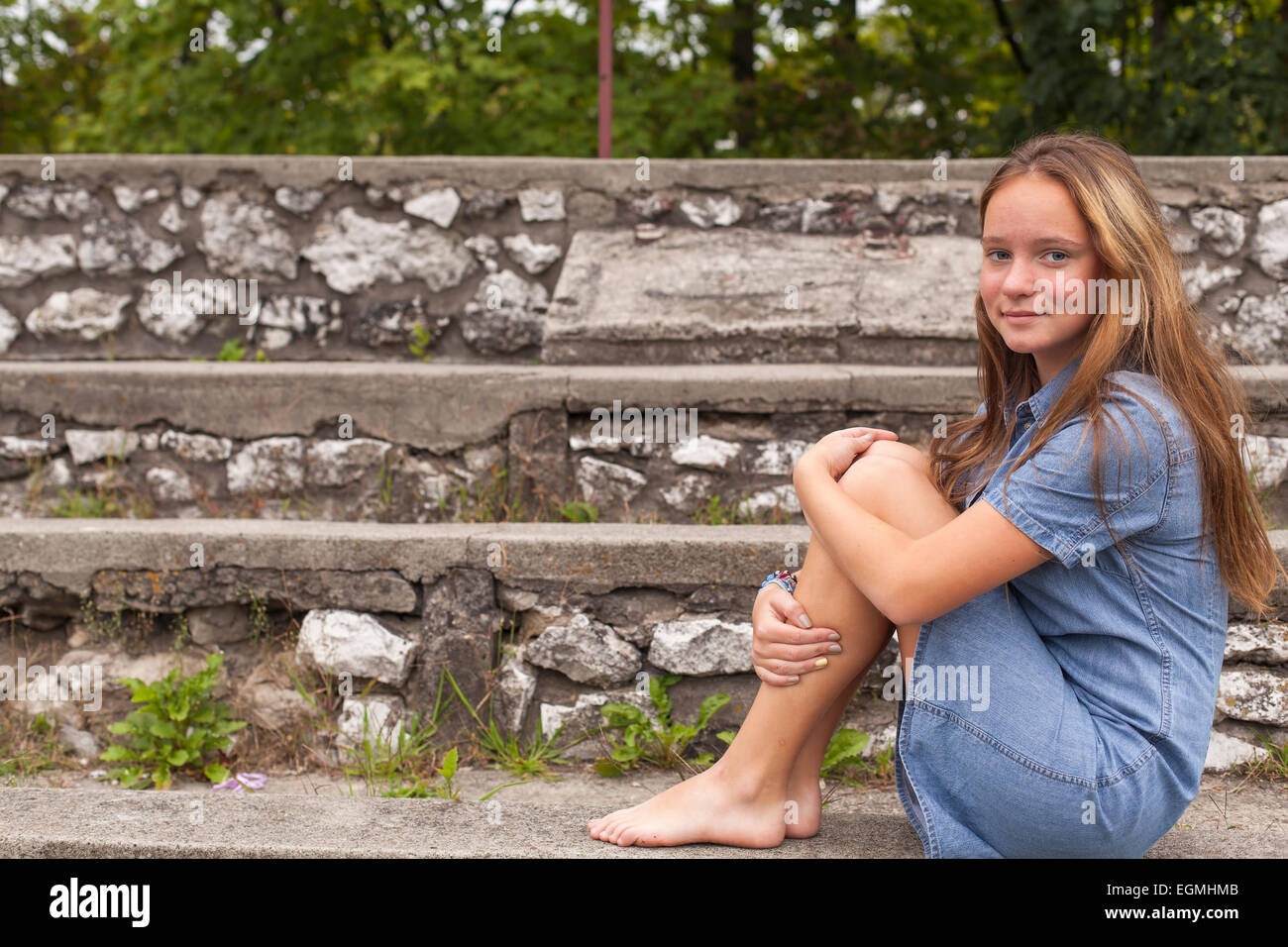 cute-young-girl-sitting-on-the-stone-steps-at-the-old-city-park-stock