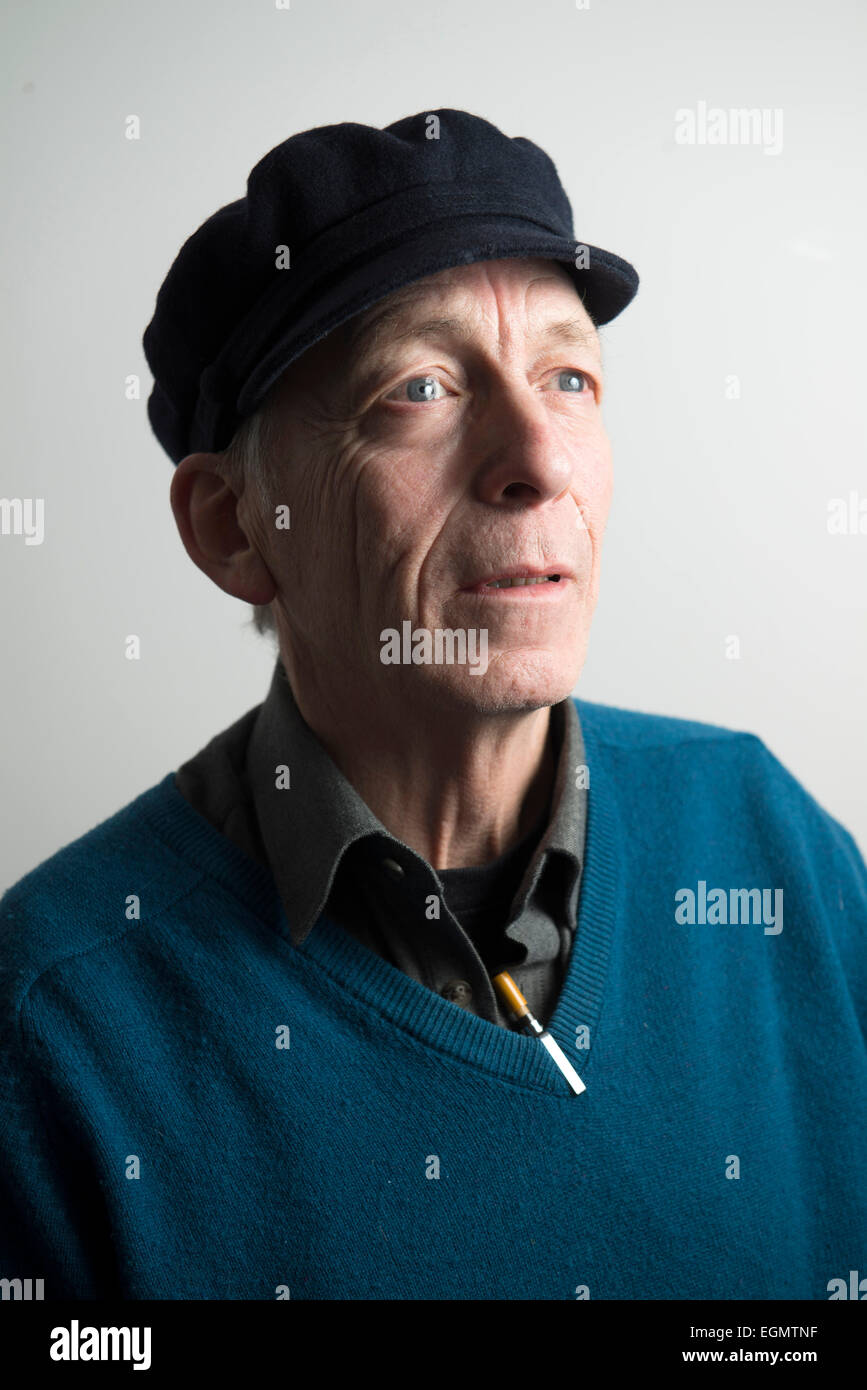 characterful funny old wise elder man in a peaked hat, v neck pullover sweater jumper, with pens looking like a mad professor Stock Photo