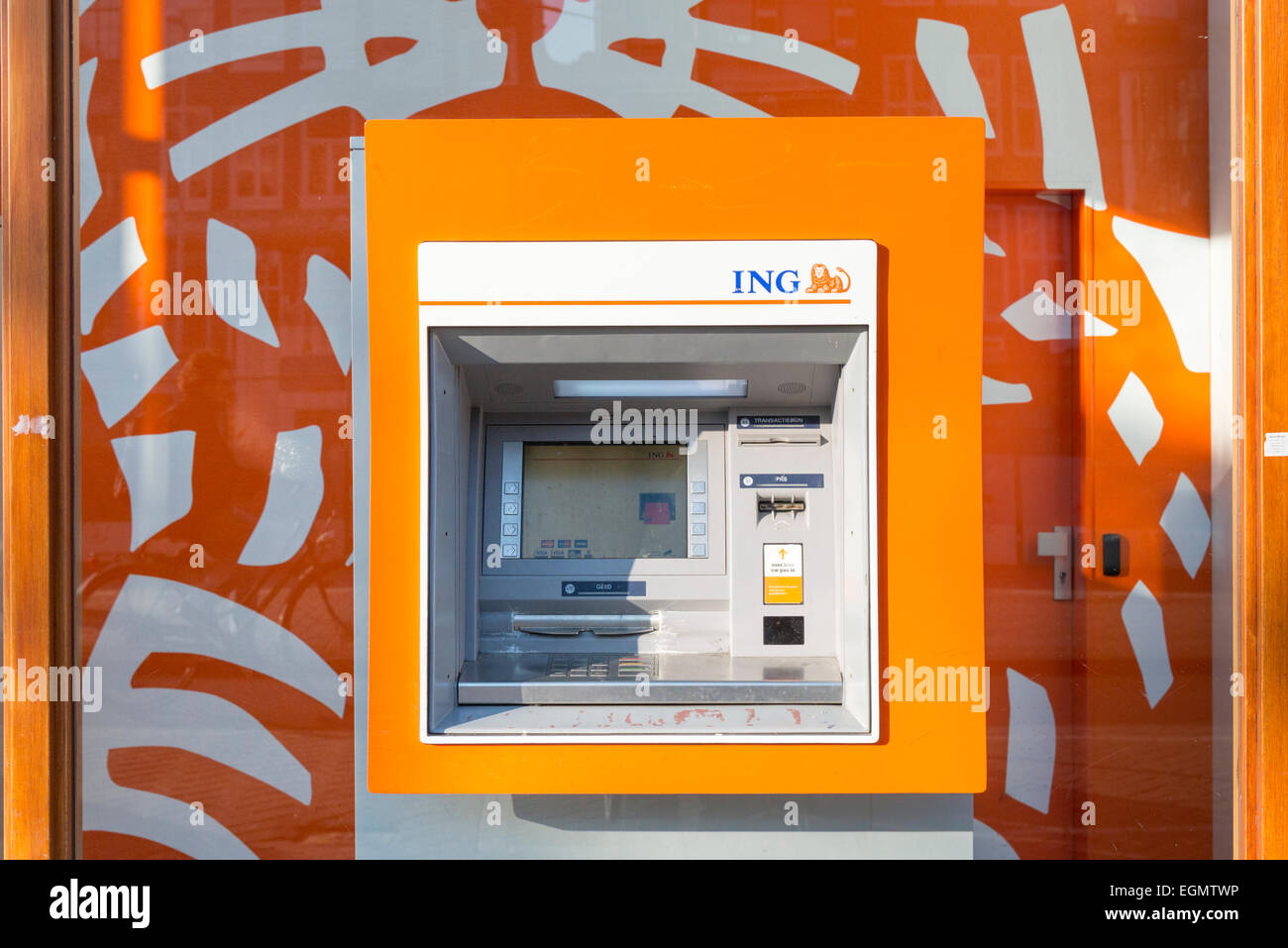 A bright orange ING ATM machine in the wall of an ING bank. Part of the Intenational Netherlands Group Stock Photo