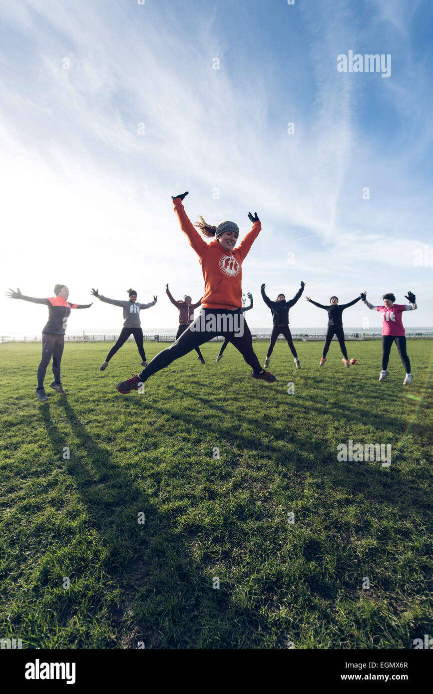 a group of girls / women take part in an out doors group fitness exercise class outside on Hove lawns on Brighton seafront Stock Photo
