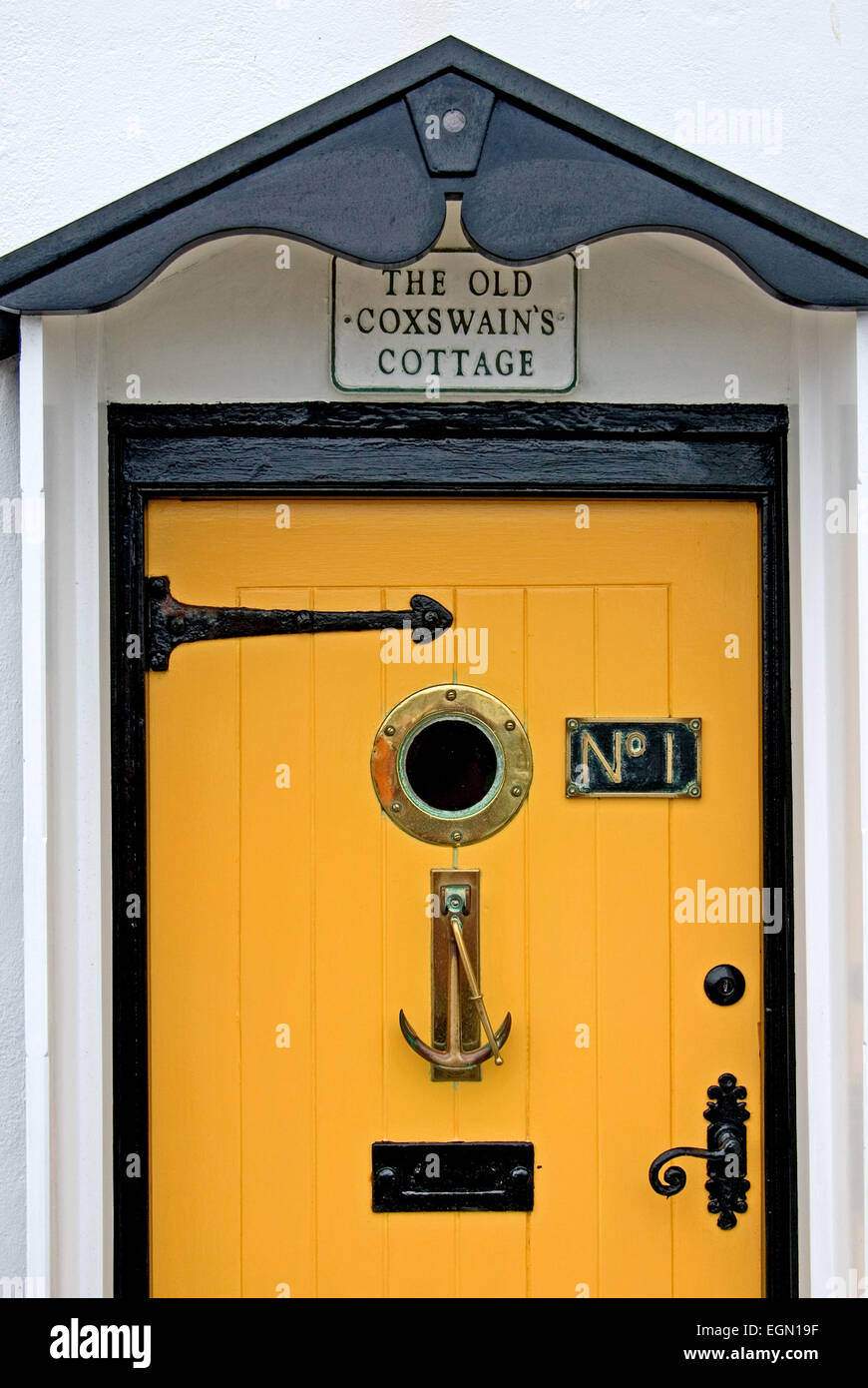 Yellow door  with porthole window and ornate door knocker Stock Photo