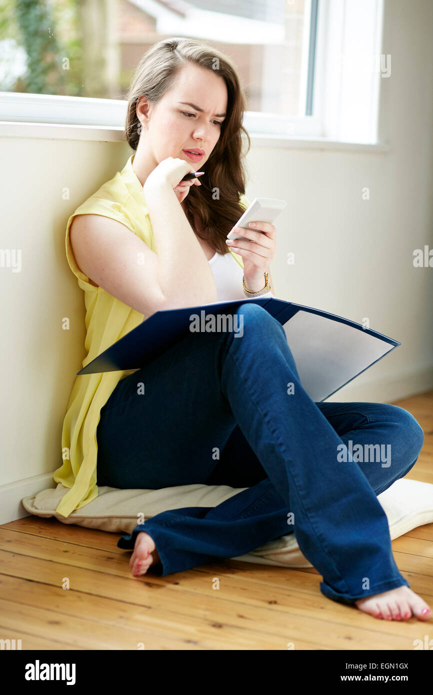 Woman working out finances sat on floor Stock Photo