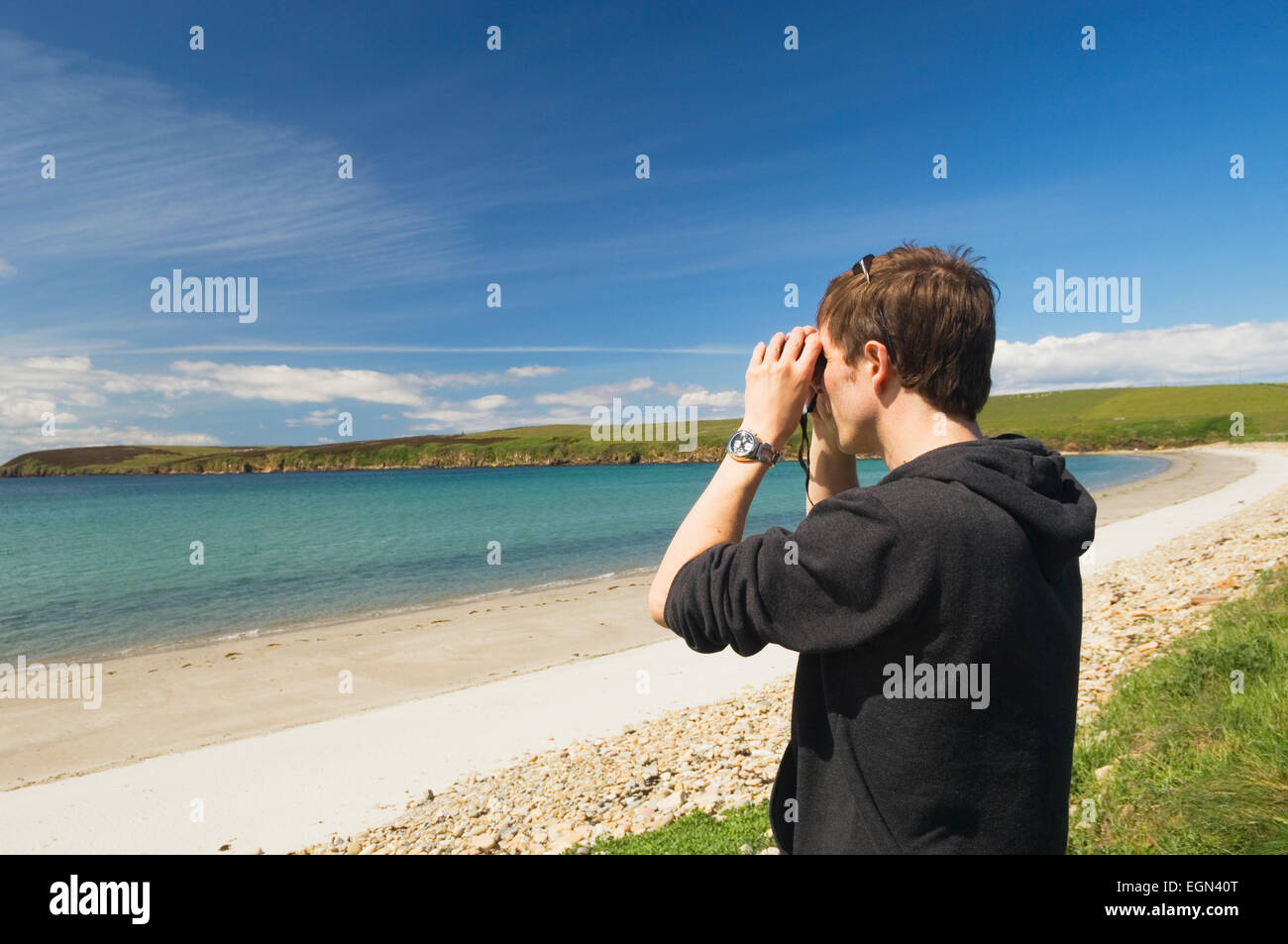 Young man birdwatching at Sands of Wright, South Ronaldsay, Orkney Islands, Scotland. Stock Photo