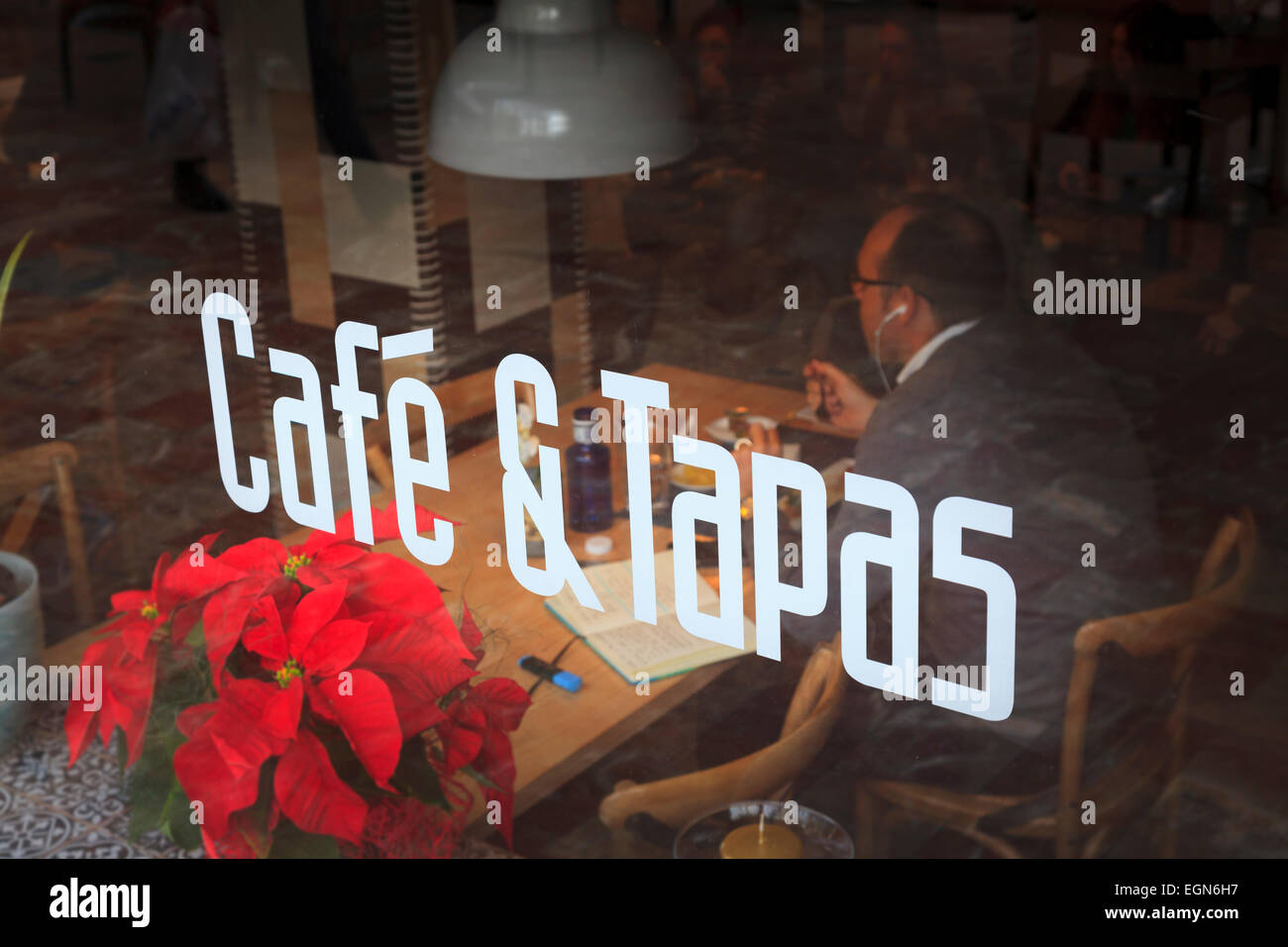 Cafe and Tapas sign on window with diner eating inside Stock Photo