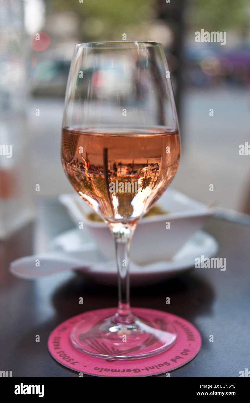 a glass of rose wine half full on a table in paris reflecting the street Stock Photo