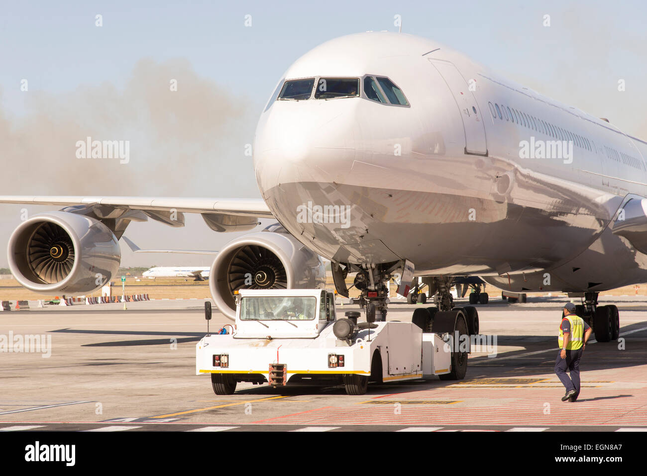 Passenger jet being towed by a tug on airport taxiway Stock Photo