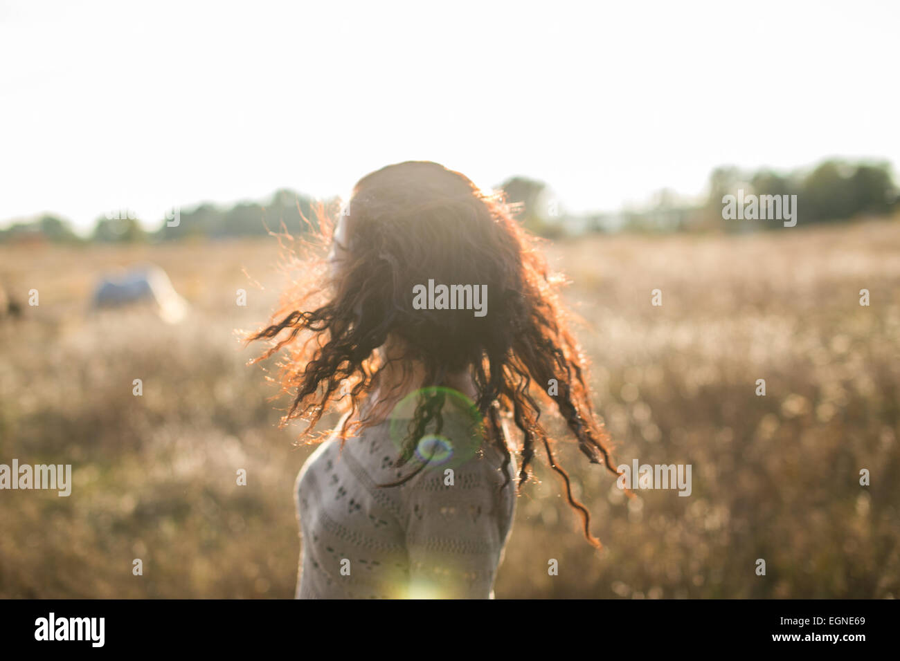 Young girl shaking her head on a walk in the field at sunset Stock Photo