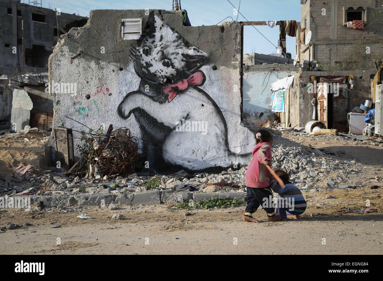Palestinian children in front of a mural of a kitten, said to have been painted by British street artist Banksy, on the remains of a house that was destroyed during the 50-day war between Israel and Hamas militants in the summer of 2014, in the Gaza Strip town of Beit Hanun. © Ahmed Hjazy/Pacific Press/Alamy Live News Stock Photo