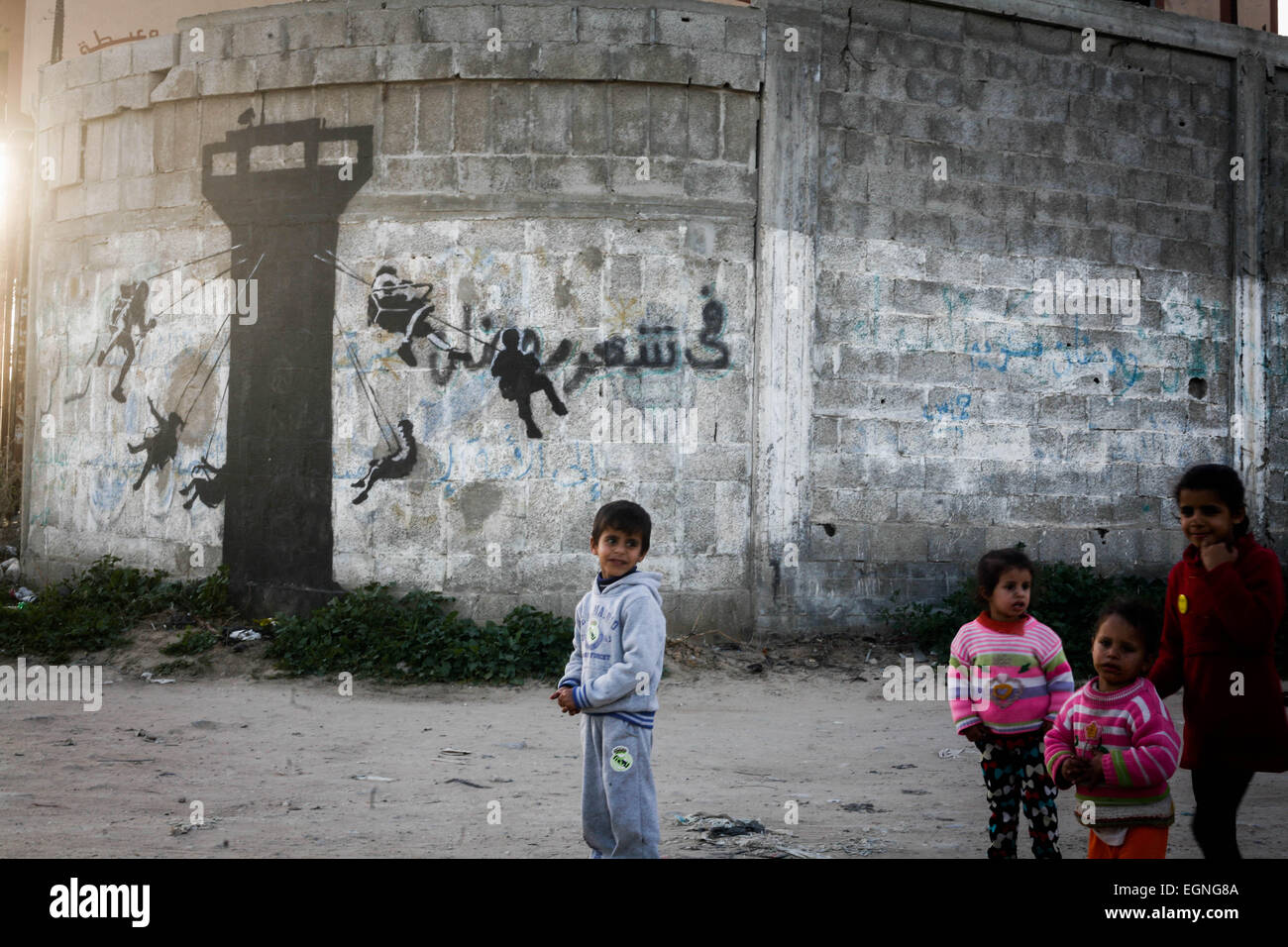 Palestinian children in front of a mural of a kitten, said to have been painted by British street artist Banksy, on the remains of a house that was destroyed during the 50-day war between Israel and Hamas militants in the summer of 2014, in the Gaza Strip town of Beit Hanun. © Ahmed Hjazy/Pacific Press/Alamy Live News Stock Photo