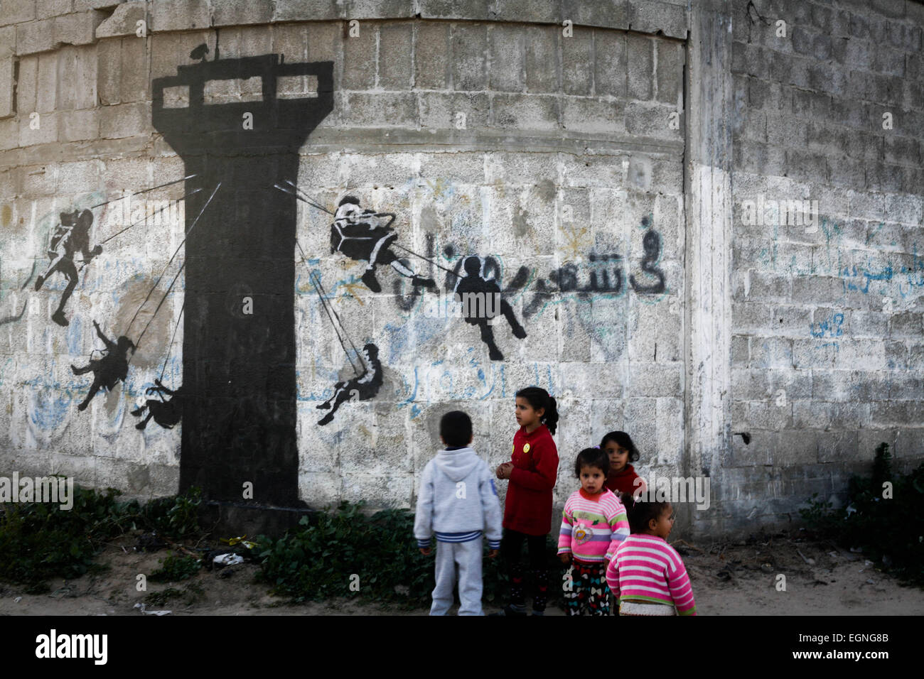 Palestinian children in front of a mural of a kitten, said to have been painted by British street artist Banksy, on the remains of a house that was destroyed during the 50-day war between Israel and Hamas militants in the summer of 2014, in the Gaza Strip town of Beit Hanun. © Ahmed Hjazy/Pacific Press/Alamy Live News Stock Photo