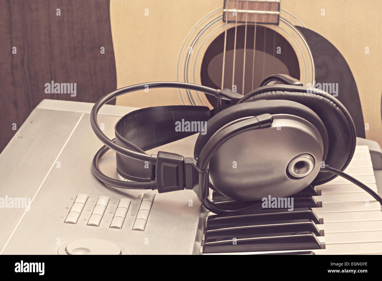 Digital midi keyboard, headphones and acoustic guitar in the studio