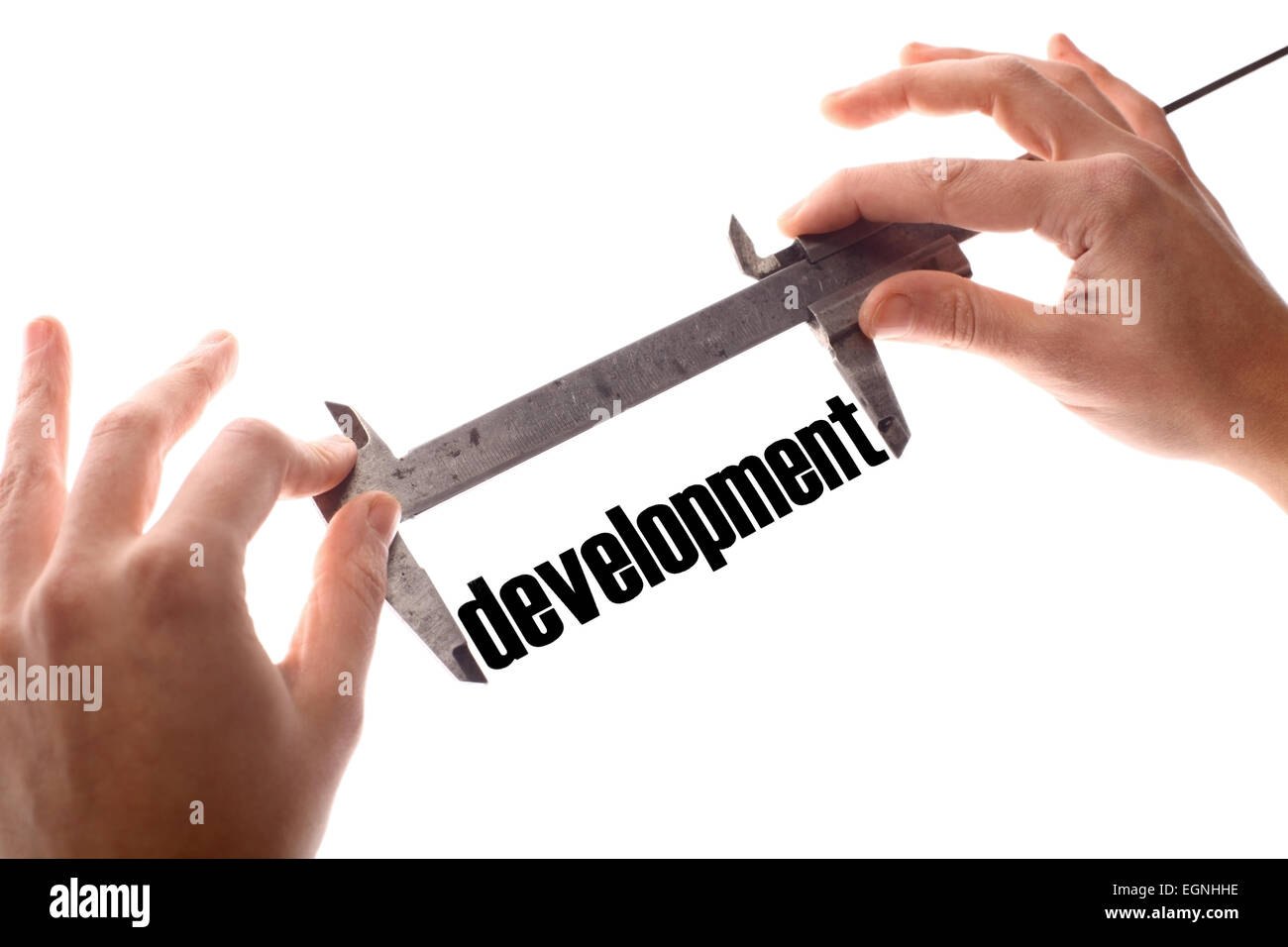 Color horizontal shot of two hands holding a caliper and measuring the word 'development'. Stock Photo