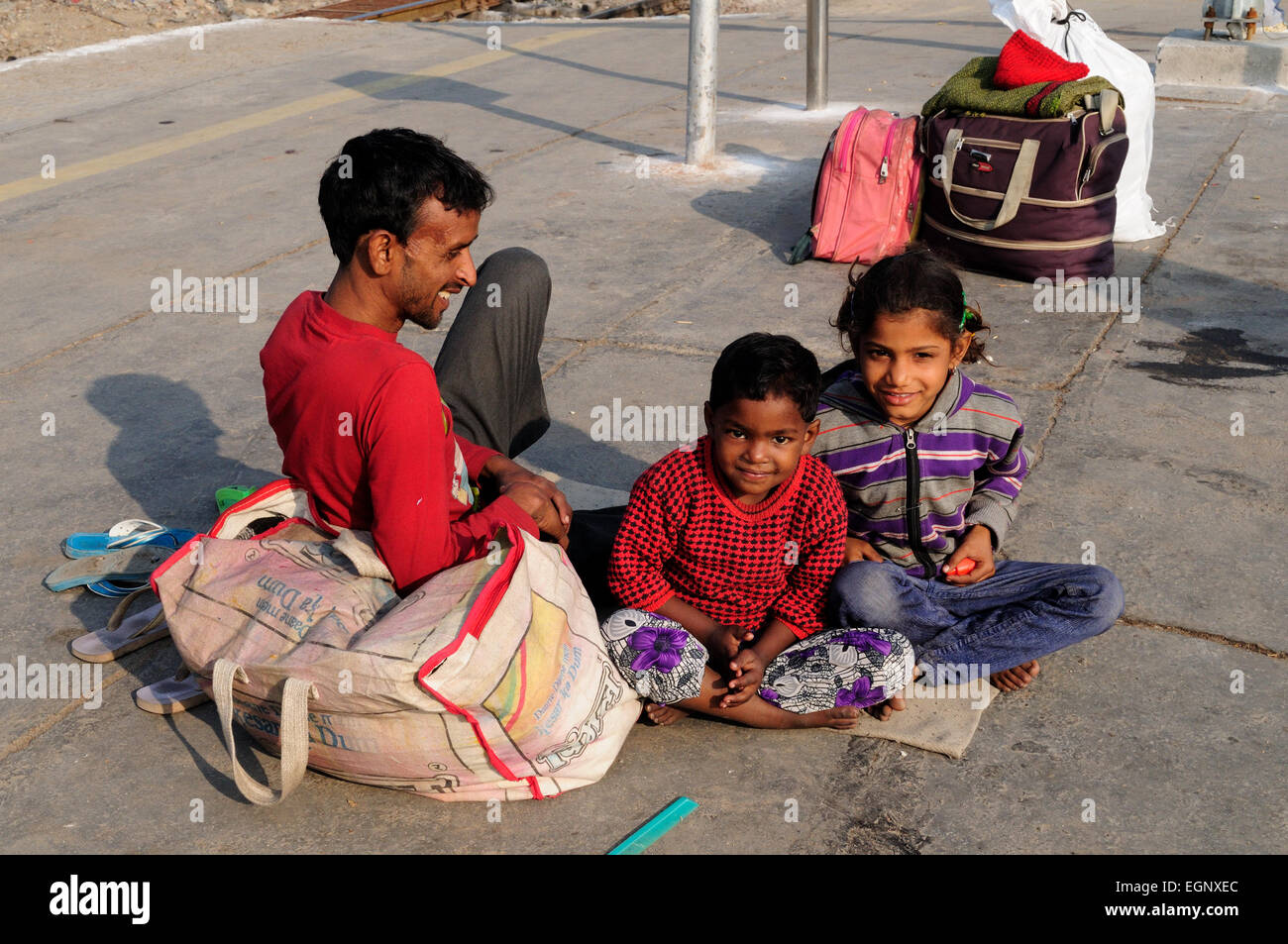 A father and his two young  children  siting on platform of Delhi Railway Station after arriving from the countryside India Stock Photo