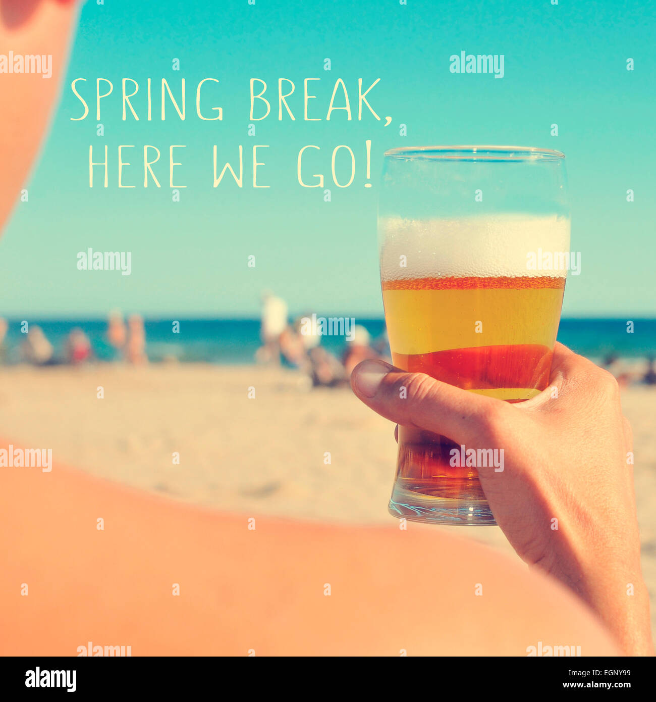 the text spring break, here we go written on a blurred image of a young man having a beer on the beach Stock Photo