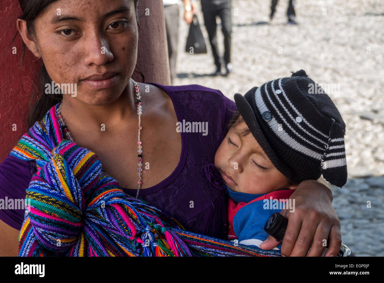 Indigenous woman carries her sleeping child in a sling in Antigua, Guatemala Stock Photo