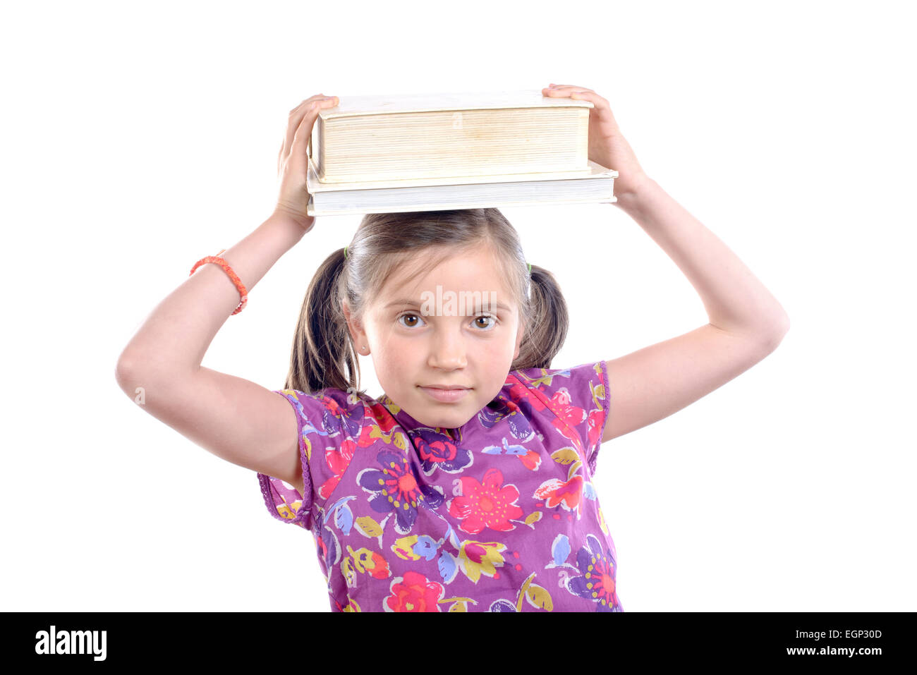 Schoolgirl with pile of books on head on white background Stock Photo ...