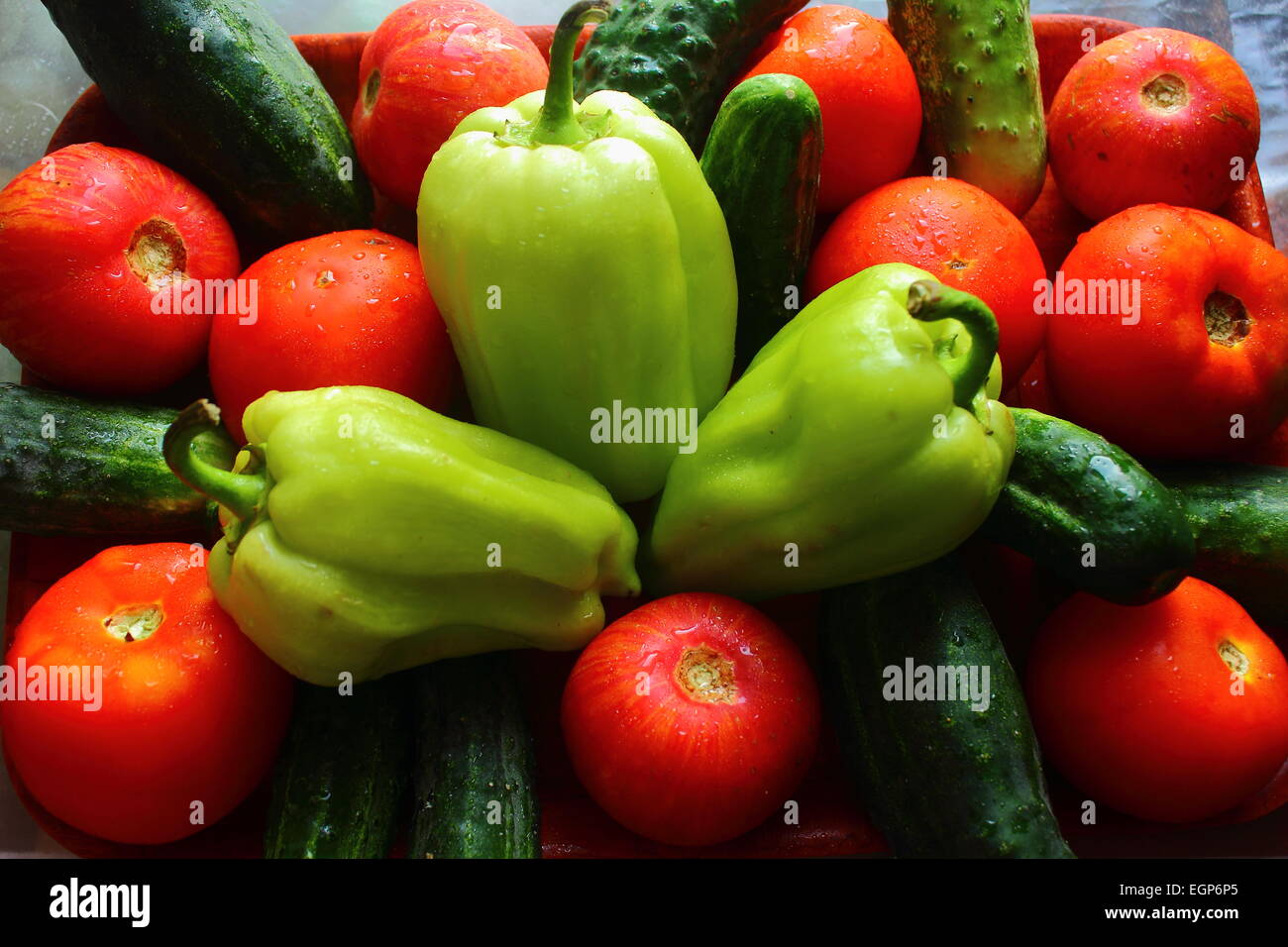 on the table are whole fresh vegetables as tomatoes, cucumbers, peppers Stock Photo