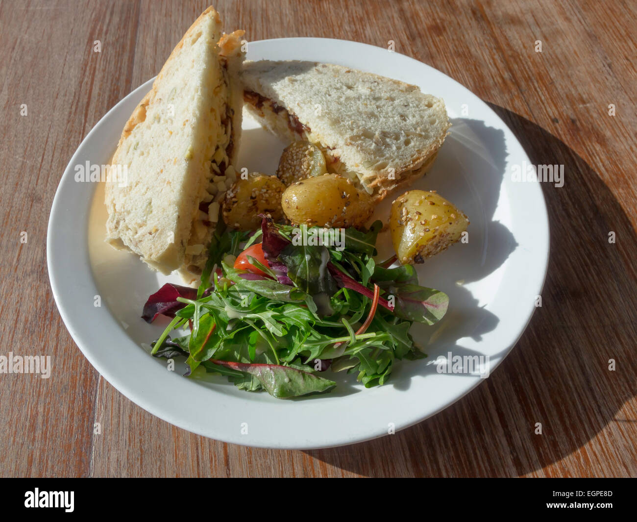Lunchtime snack Cheddar cheese and date chutney sandwich in granary bread with mixed salad and sesame potatoes in a café Stock Photo