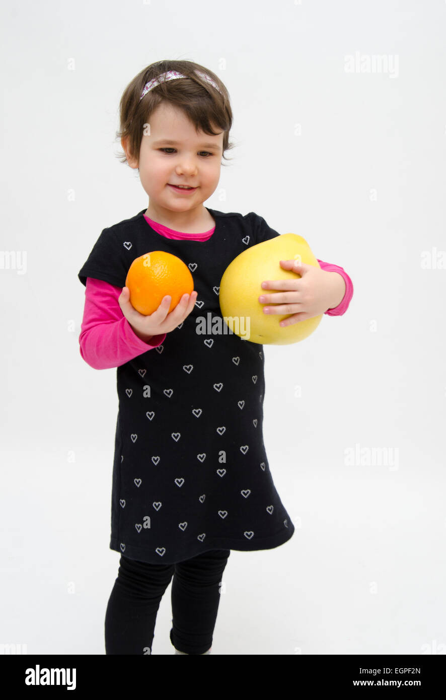 Happy little girl carrying orange and pomelo isolated on white backgroud Stock Photo