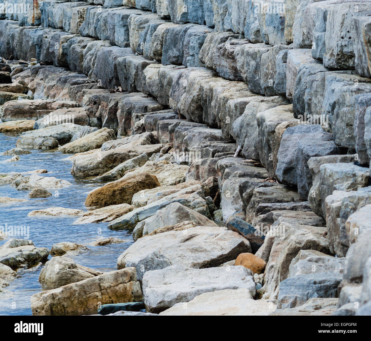 Curving breakwall of stacked stones on water. Stock Photo
