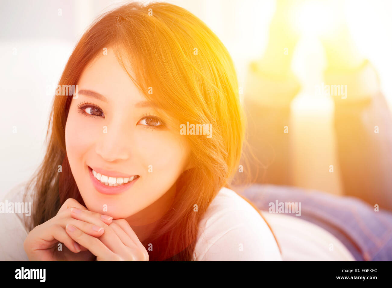 smiling Young woman  lying on the sofa with sunlight background Stock Photo