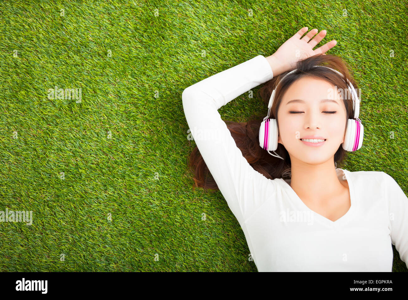 Relaxed woman listening to the music with headphones lying on the grass Stock Photo