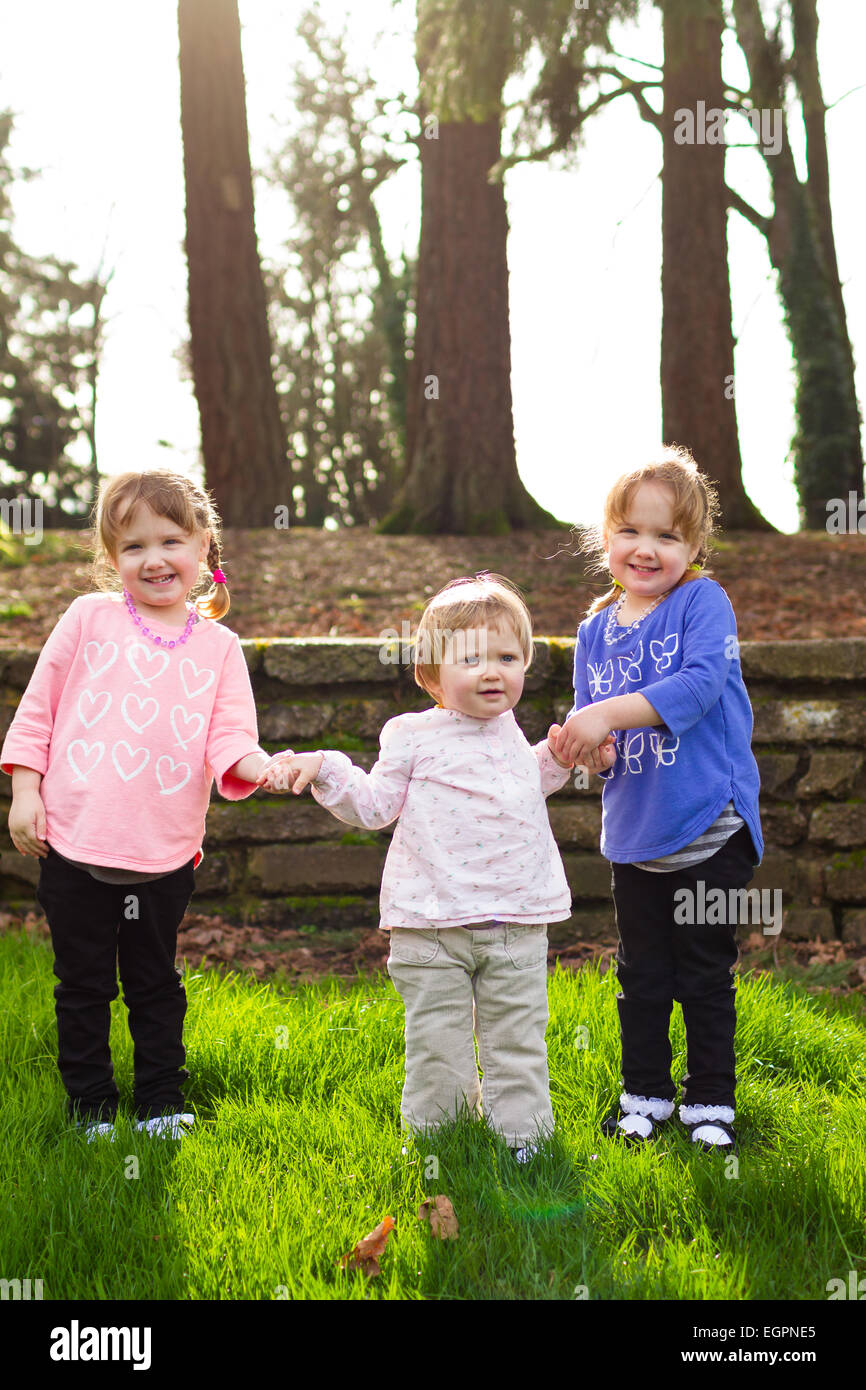 Three sisters together at a park having fun together in natural light. Stock Photo