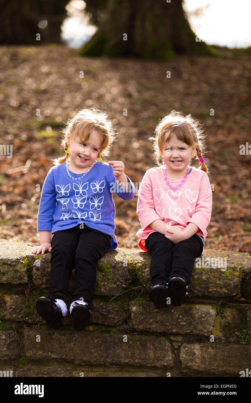 Lifestyle portrait of identical twin sisters at a park interacting and having fun together. Stock Photo