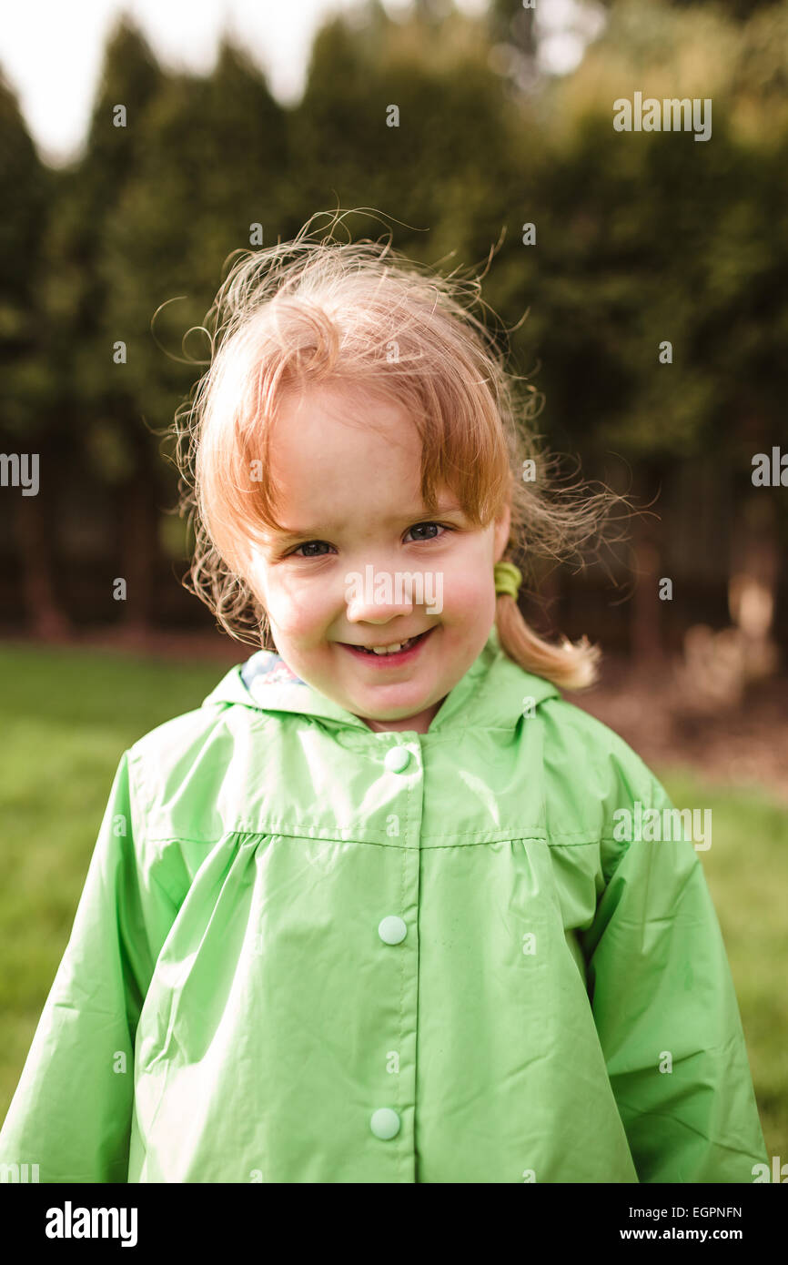 Portrait of a young girl at a park with a rain coat on. This lifestyle photo was shot with natural light. Stock Photo