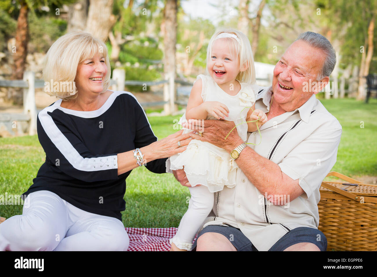 Affectionate Granddaughter and Grandparents Playing Outside At The Park. Stock Photo