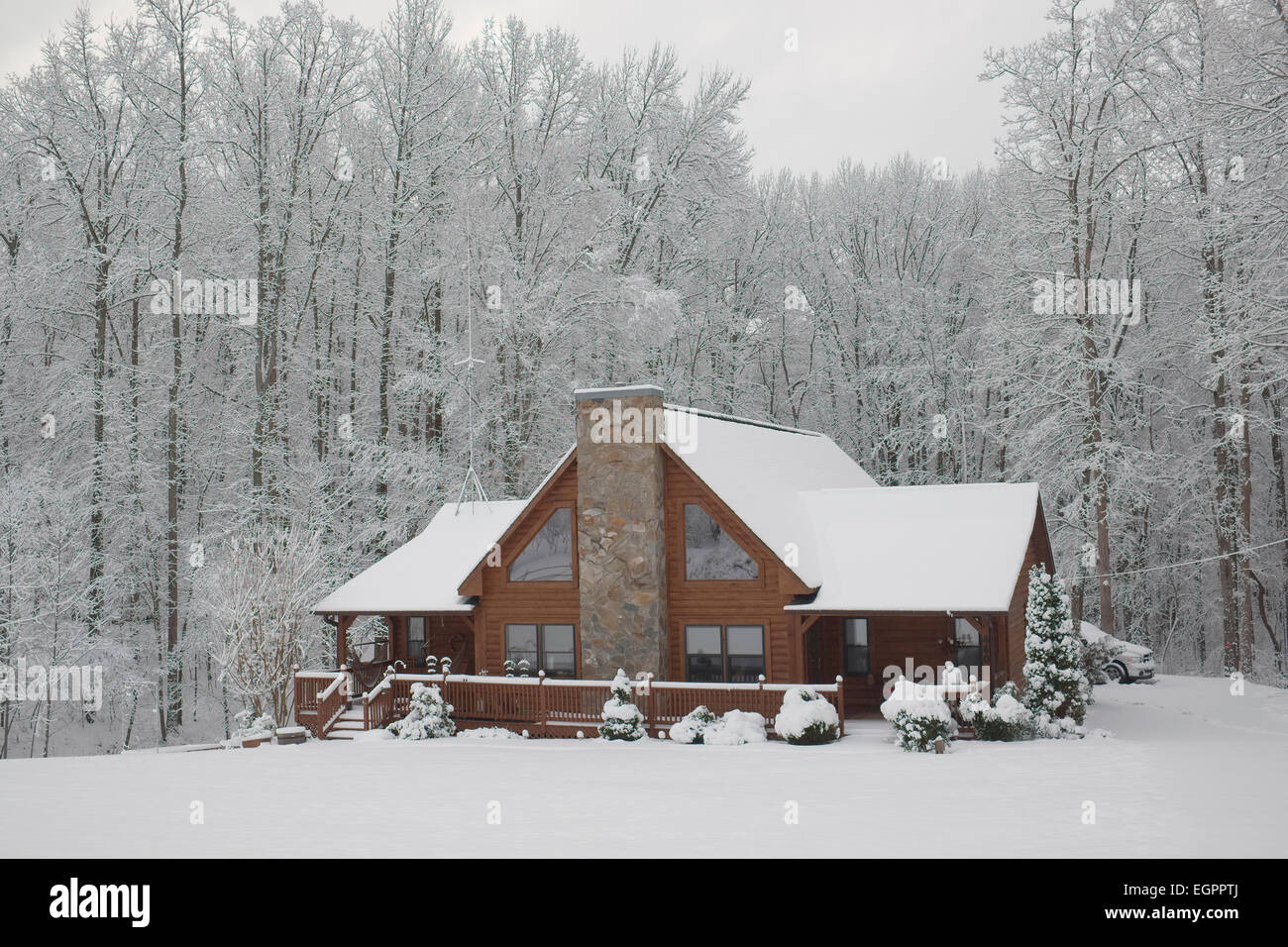 Snow covered log home in North Carolina. Surrounded by trees. Stock Photo