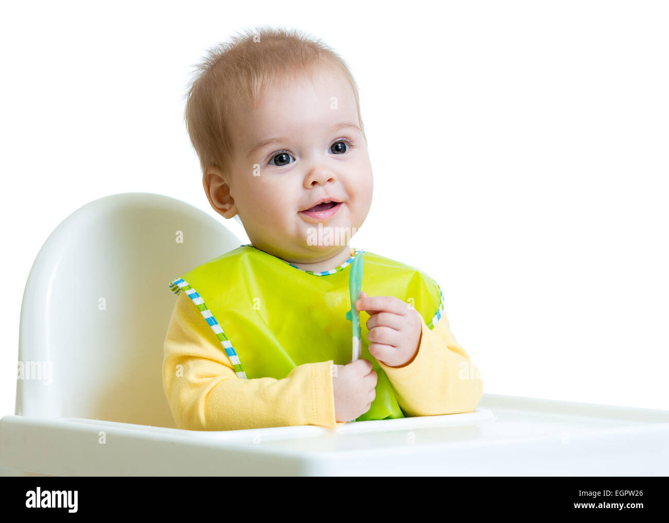 happy baby child sitting in chair with a spoon Stock Photo