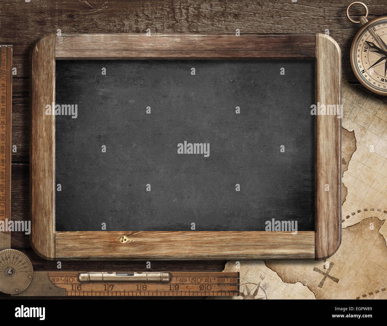 Treasure map, blackboard, old compass and ruler on wood desk. Adventure or discovery concept. Stock Photo