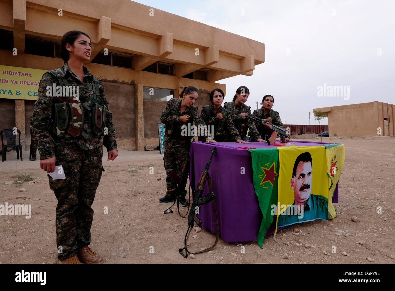 Kurdish fighters of the Women's Protection Units YPJ taking part in a swearing process over a flag bearing the figure of former PKK militant leader Abdullah Ocalan in a training camp in Al Hasakah or Hassakeh district in northern Syria Stock Photo