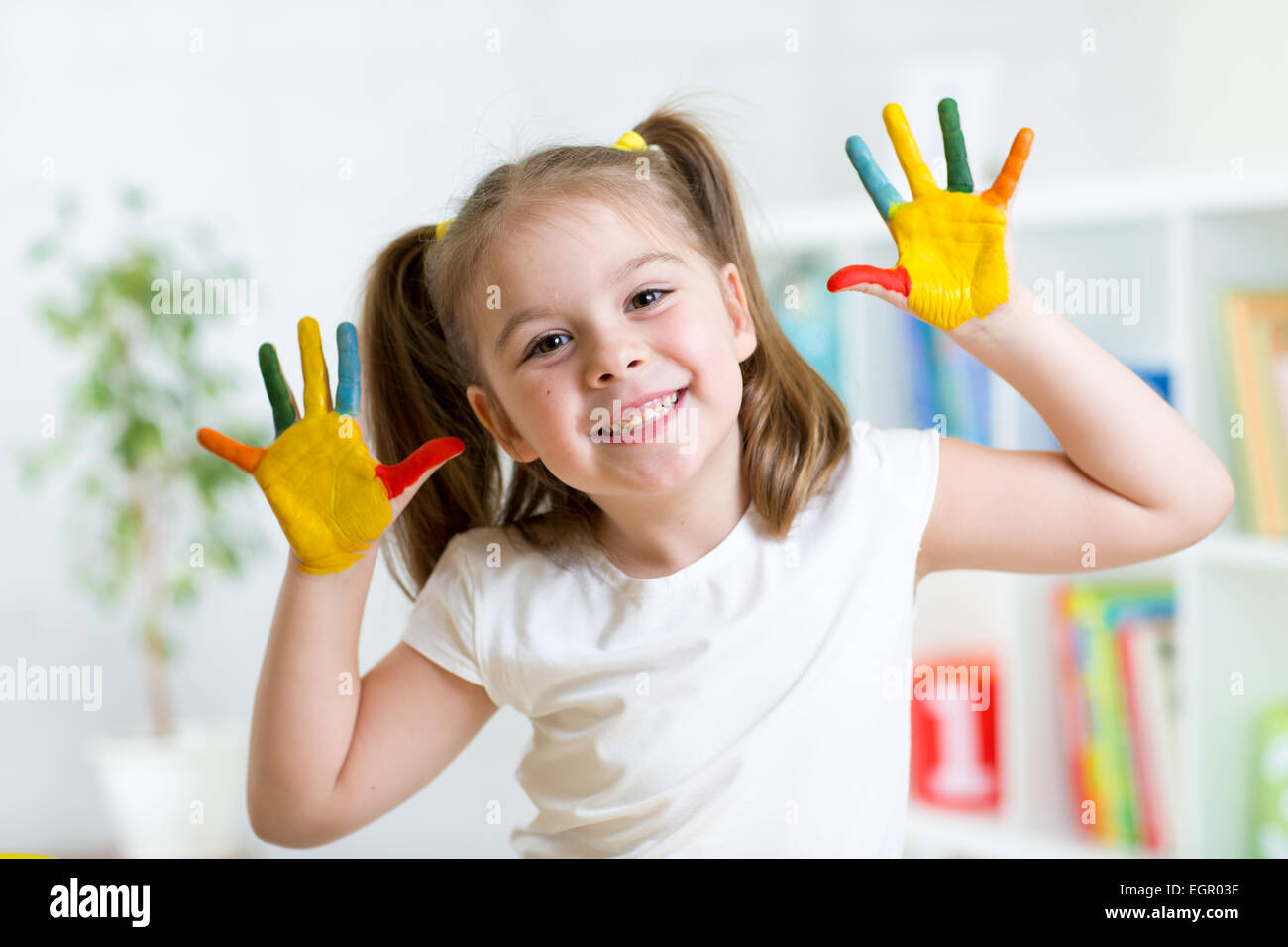 little girl with color hands in paint Stock Photo