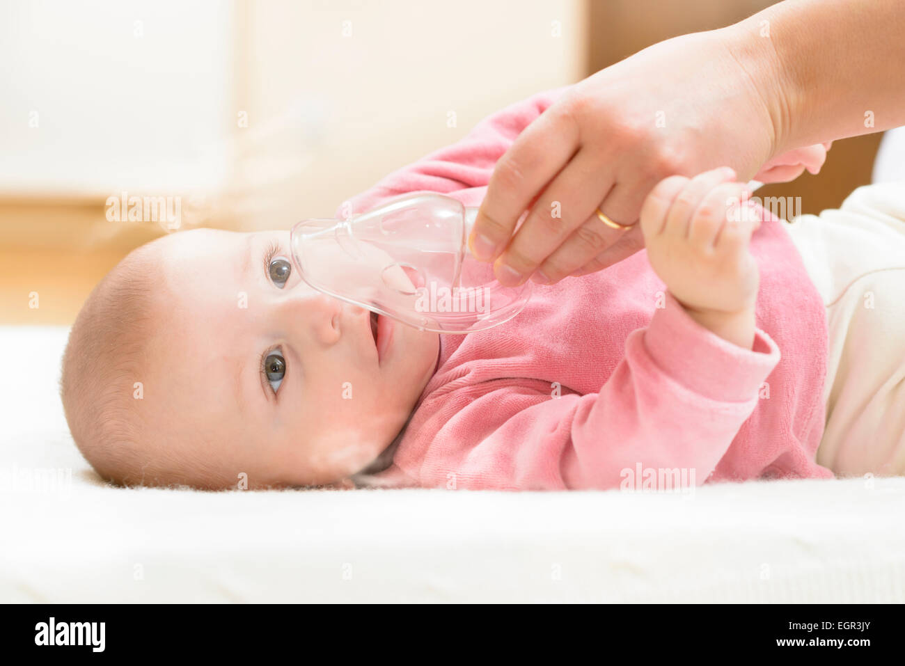 Baby taking respiratory therapy. Hand holding the mask of a nebuliser. Stock Photo