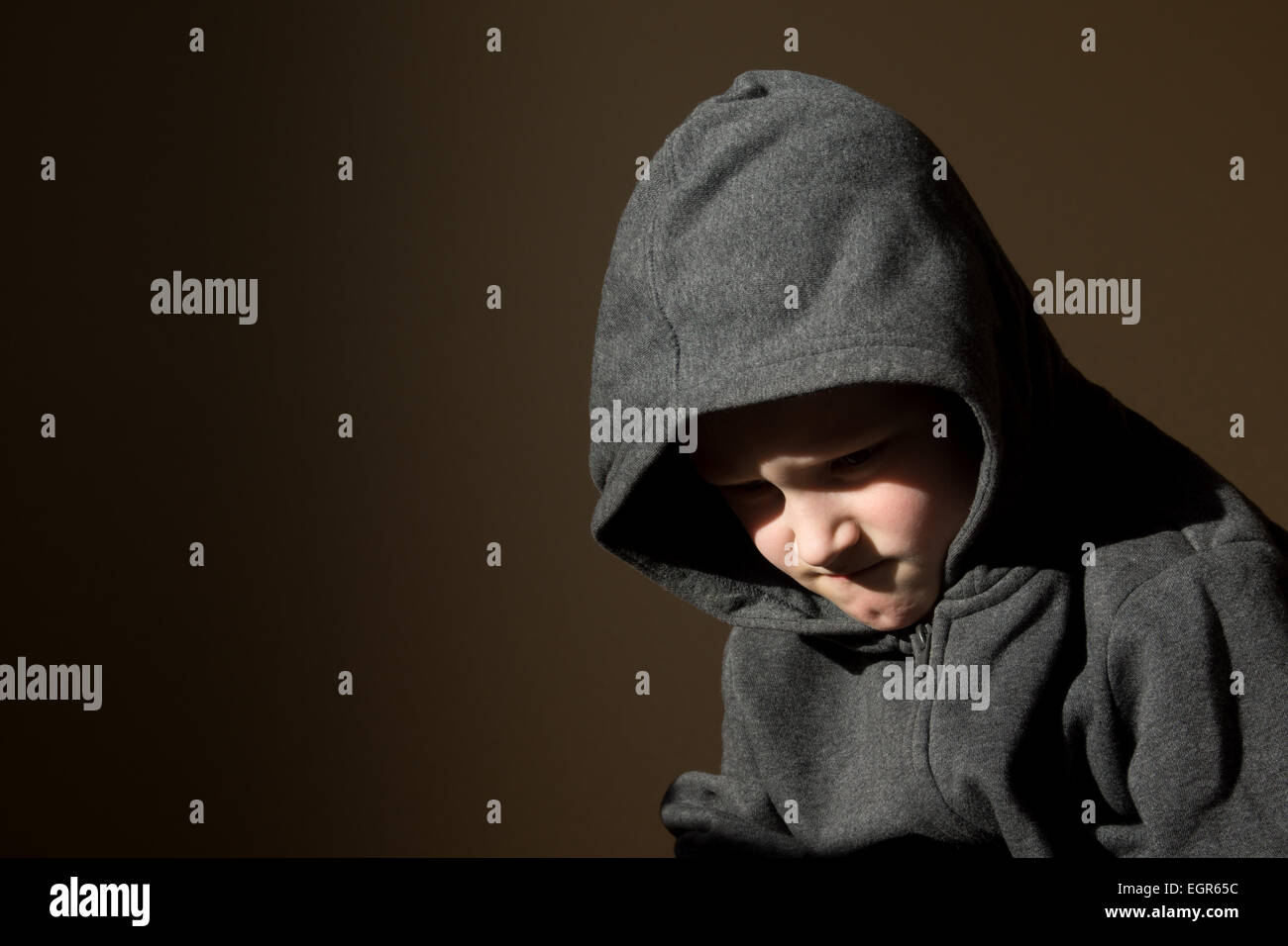 Sad upset tired worried unhappy little child (boy) close up horizontal dark portrait with copy space Stock Photo