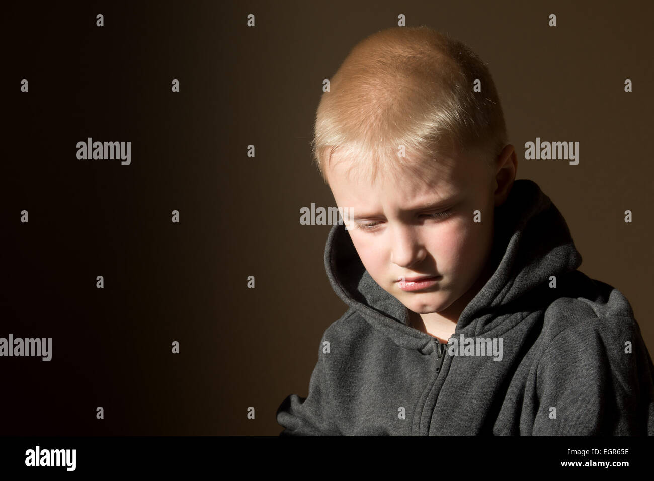 Sad upset tired worried unhappy little child (boy) close up horizontal dark portrait with copy space Stock Photo