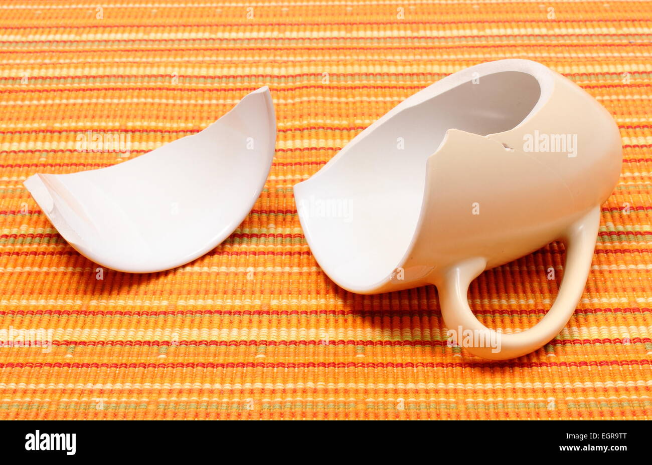 Closeup of broken cup, shattered cup, damaged mug lying on orange cloth