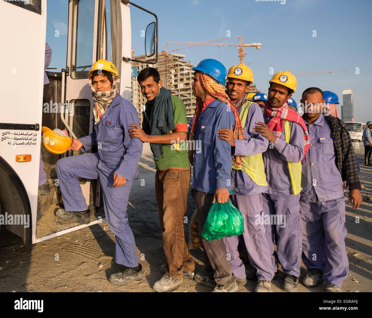 Construction workers queuing to get on bus to living quarters at end of