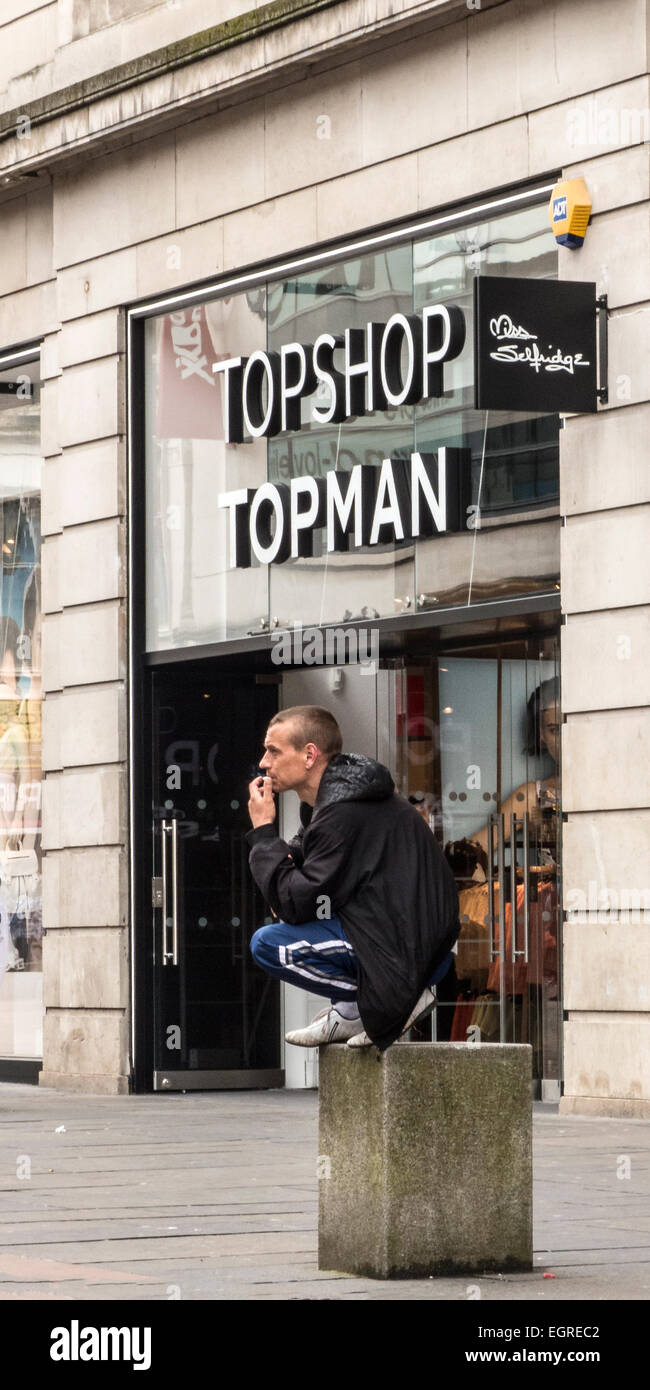 Man crouched on concrete block in Glasgow, he remained in this for over 30 minutes. Stock Photo