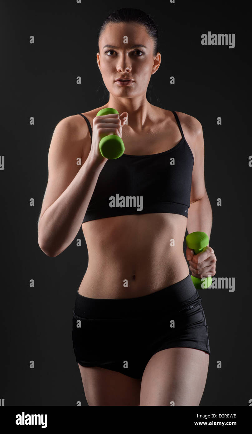 Fitness woman working out with green dumbbell. Running model Stock Photo