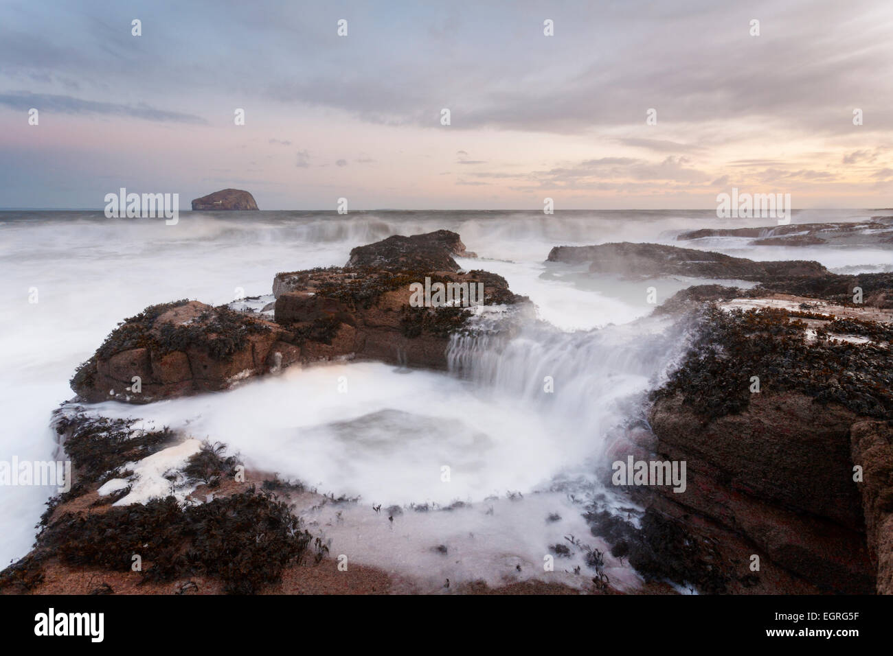 A large wave causes a tidal pool to fill up, Seacliff Beach. Stock Photo
